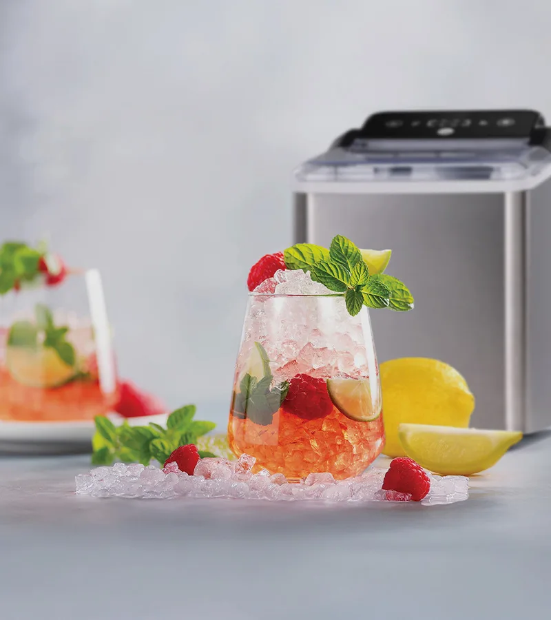 Uppfriskande dryck med krossad is, hallon, lime, mynta, en ismaskin och utspridd is med citron.